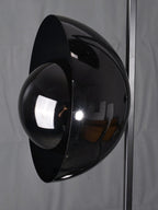 Macro close-up of the Clérachic floor lamp's glossy black dome shade, showing its curved metal and glass finish.