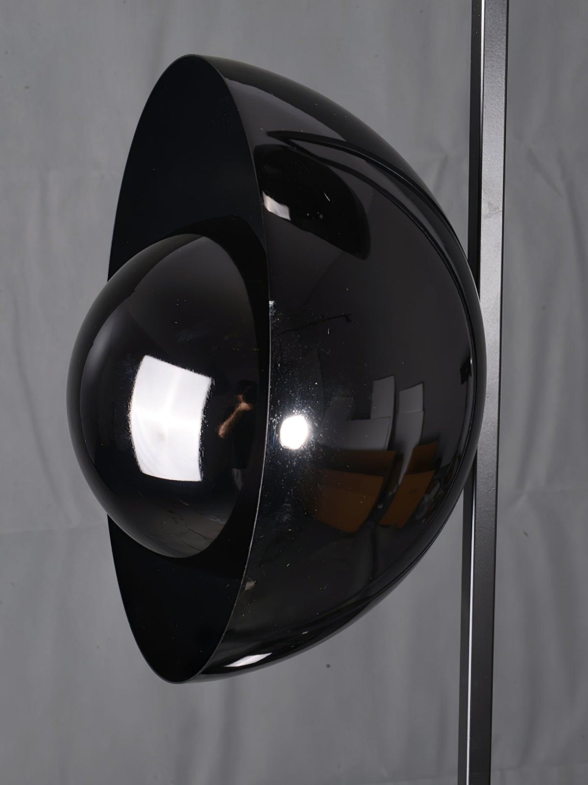 Macro close-up of the Clérachic floor lamp's glossy black dome shade, showing its curved metal and glass finish.
