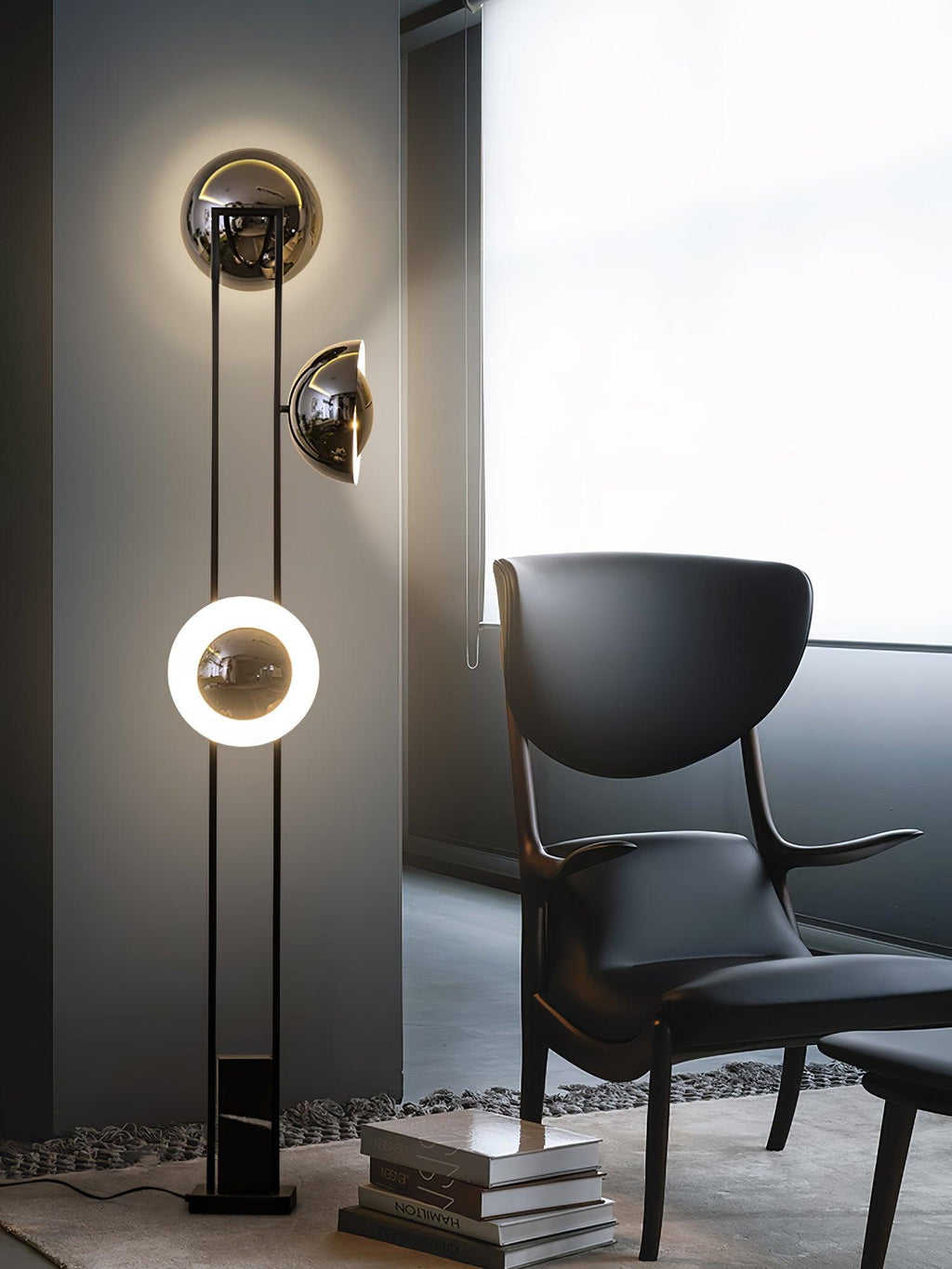 Clérachic floor lamp with all three heads lit, standing beside a dark leather chair and a stack of books.