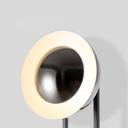 Extreme close-up of the Clérachic floor lamp's lit ring, its warm white halo glowing inside a dark dome shade.