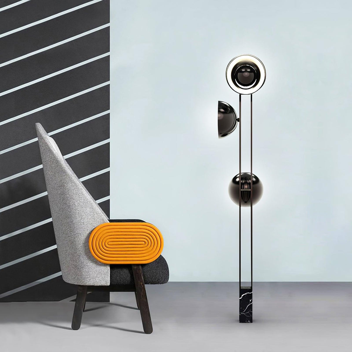 Clérachic floor lamp with its top dome lit gold, standing beside a grey chair with an orange accent stool.