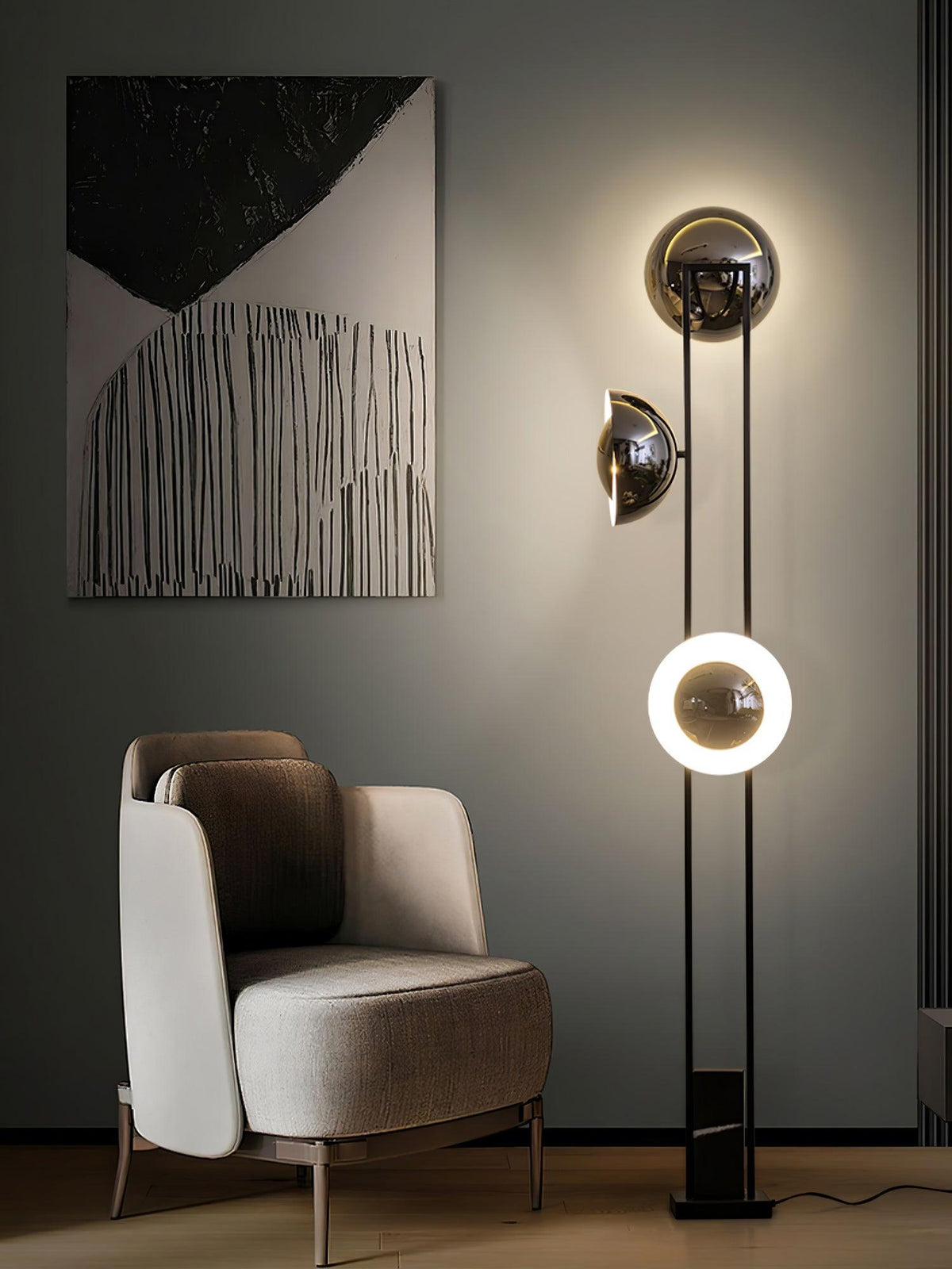 Clérachic floor lamp with its lower ring lit warm white, standing beside a taupe armchair and an abstract painting.