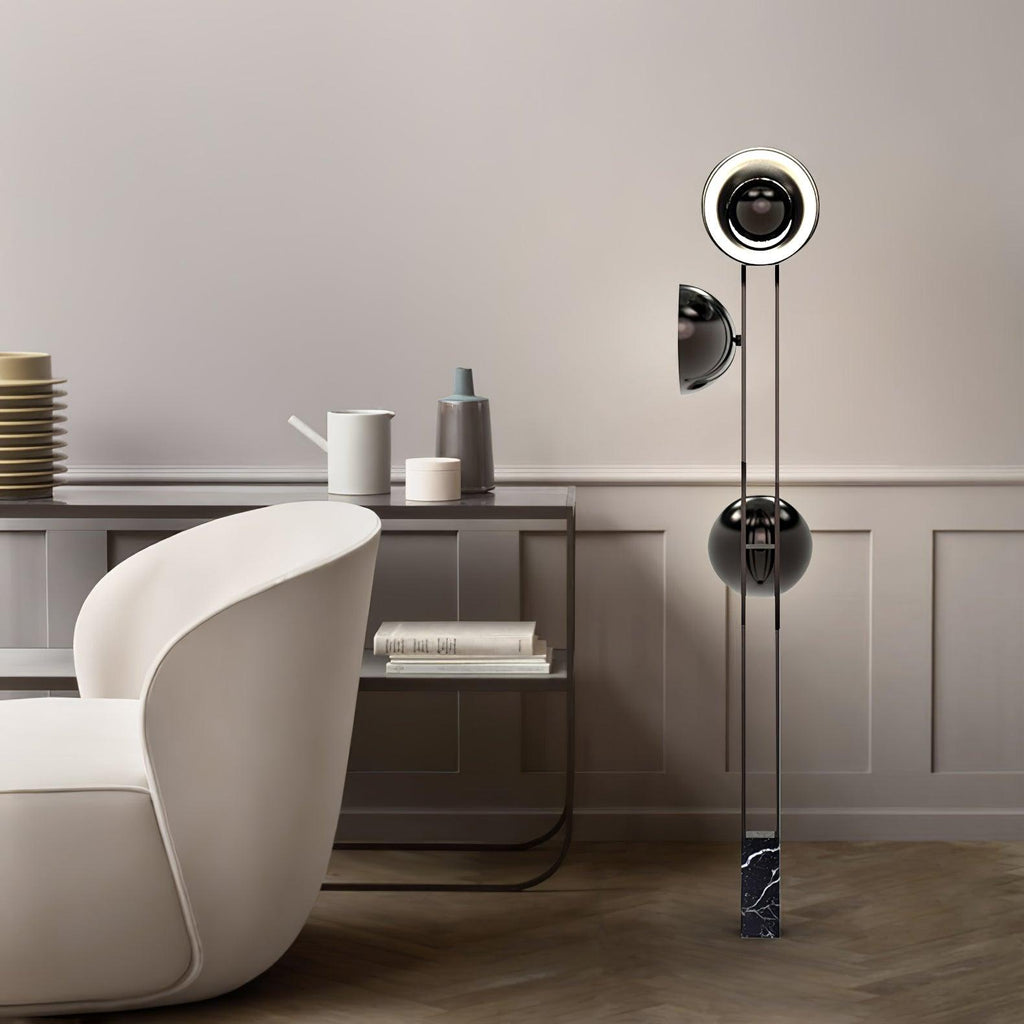 Full-height view of the Clérachic floor lamp, top ring lit warm white, beside a round table with ceramics in a bright room.