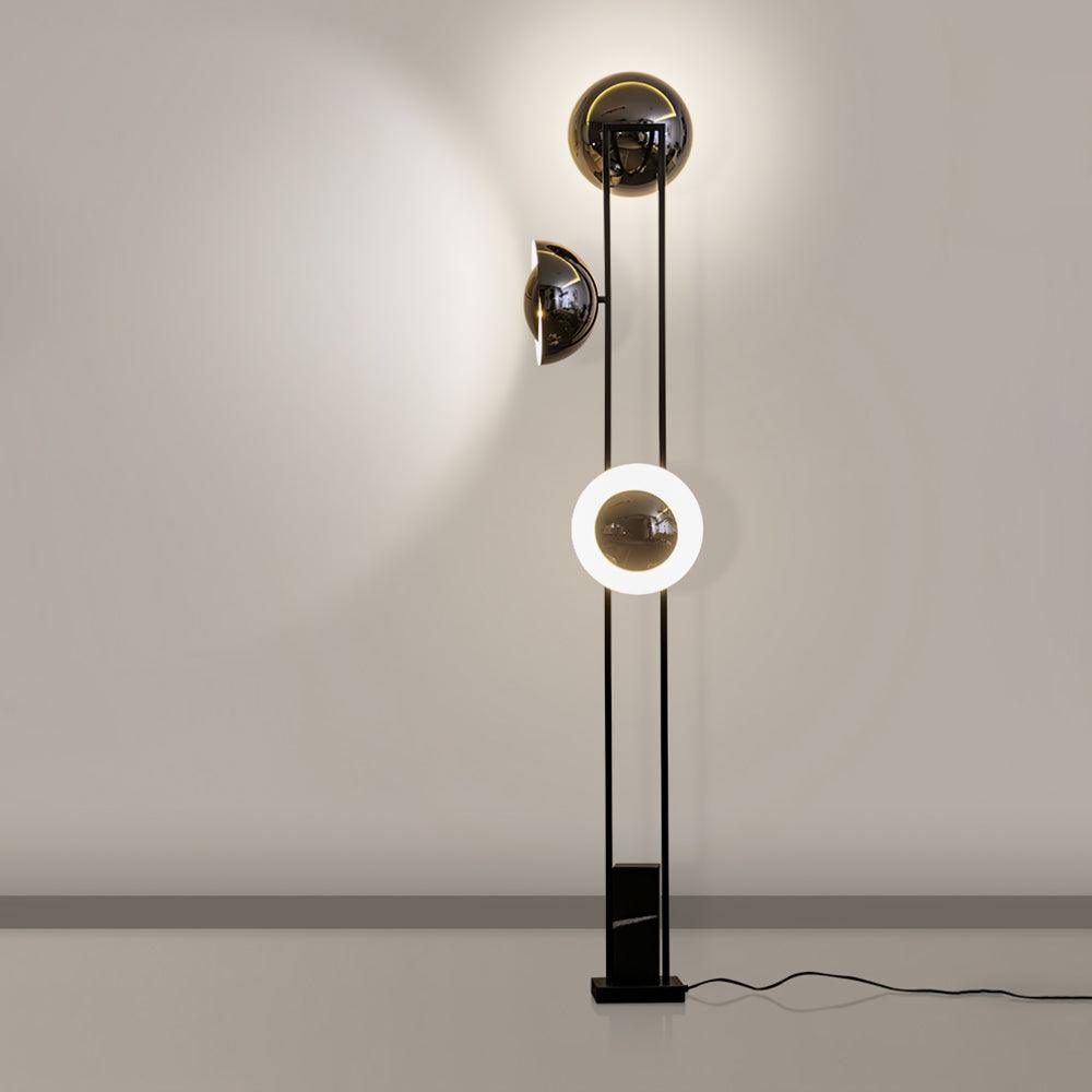 Clérachic floor lamp against a plain wall, its lower ring glowing warm white beneath two unlit dome shades.