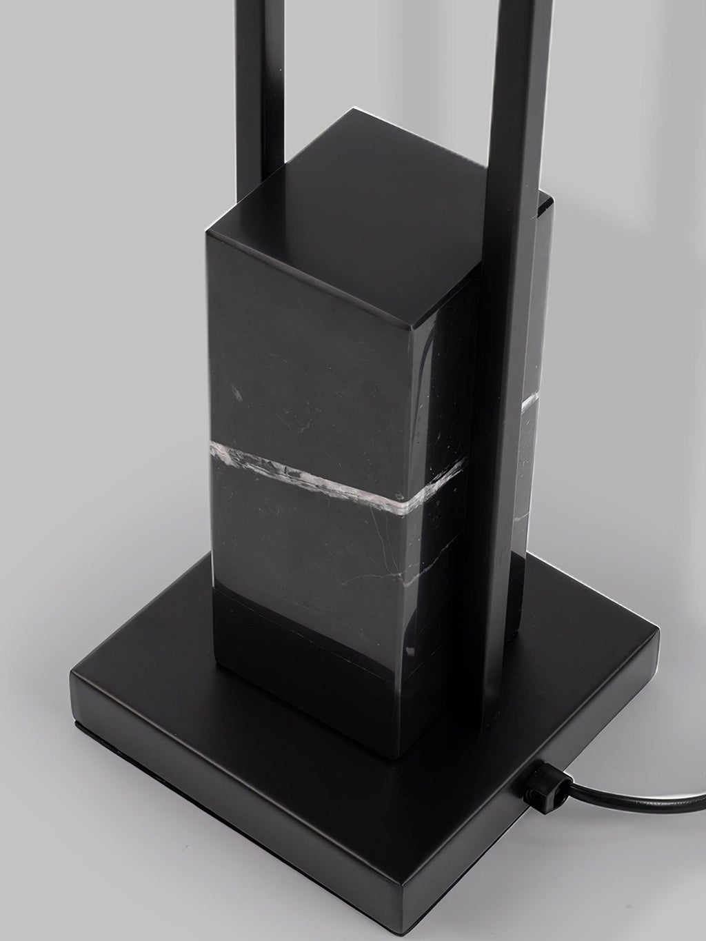 Close-up of the Clérachic floor lamp's black marble base and square foot, showing the mains cord and metal column.