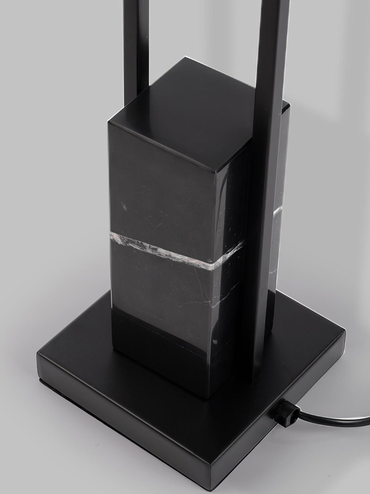 Close-up of the Clérachic floor lamp's black marble base and square foot, showing the mains cord and metal column.