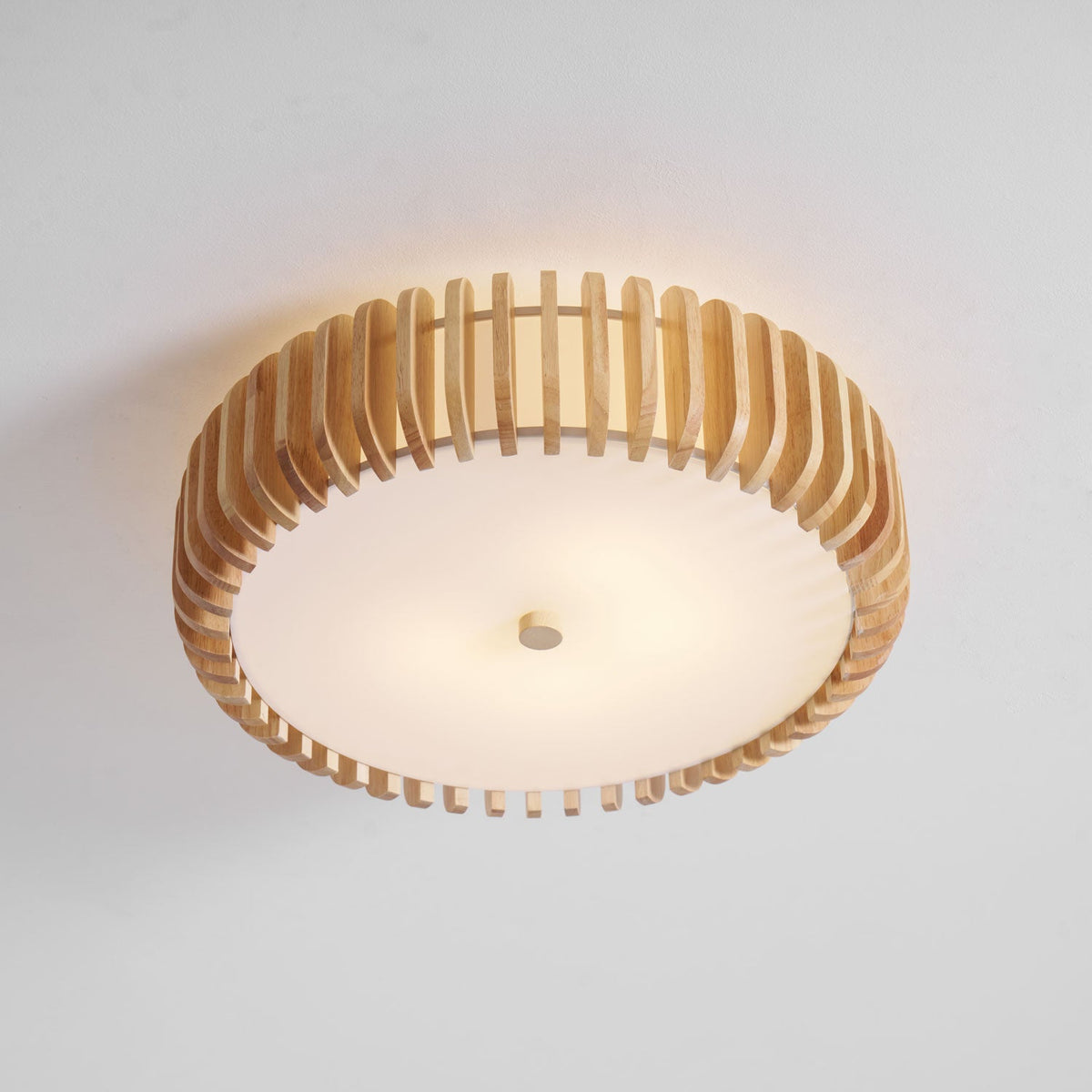 Seen from below in the studio, this Clérachic ceiling light glows lit, slats framing the diffuser.
