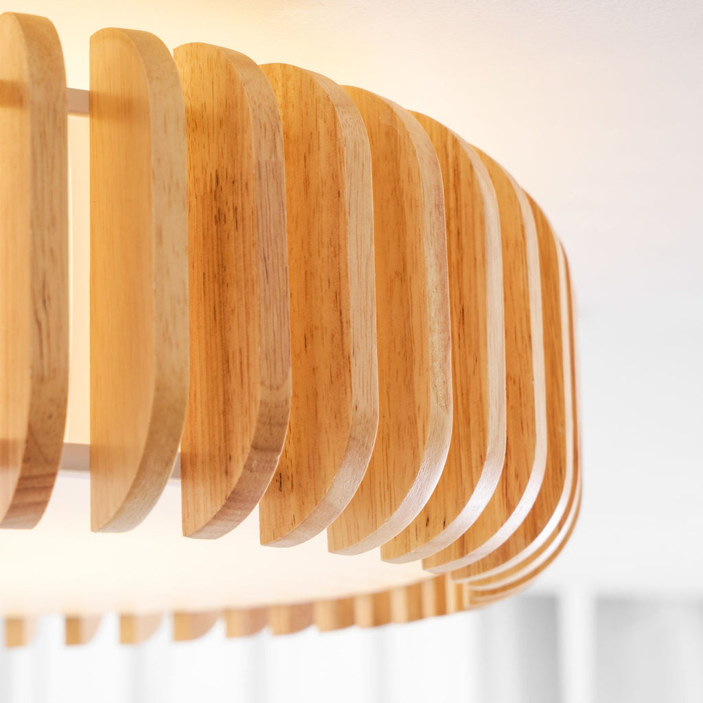 Close view of the fanned wood slats on this Clérachic ceiling light against a curtained window.