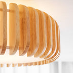Close view of the fanned wood slats on this Clérachic ceiling light against a curtained window.