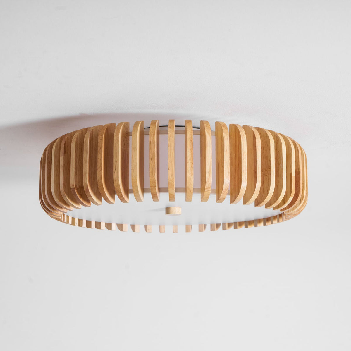 Overhead studio view of this Clérachic ceiling light, lit, wood slats spread in a wide oval.