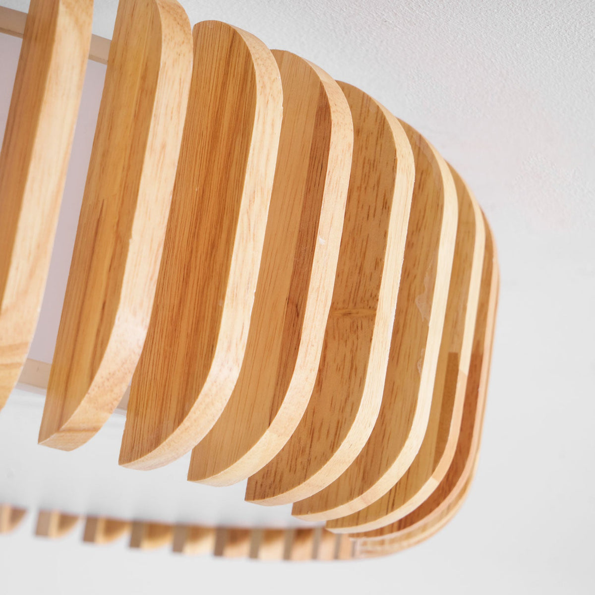 Close view of the wood slats on this Clérachic ceiling light, curving outward from below.