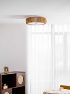 Seen small in a room corner, this Clérachic ceiling light hangs near sheer curtains and a dark cabinet.