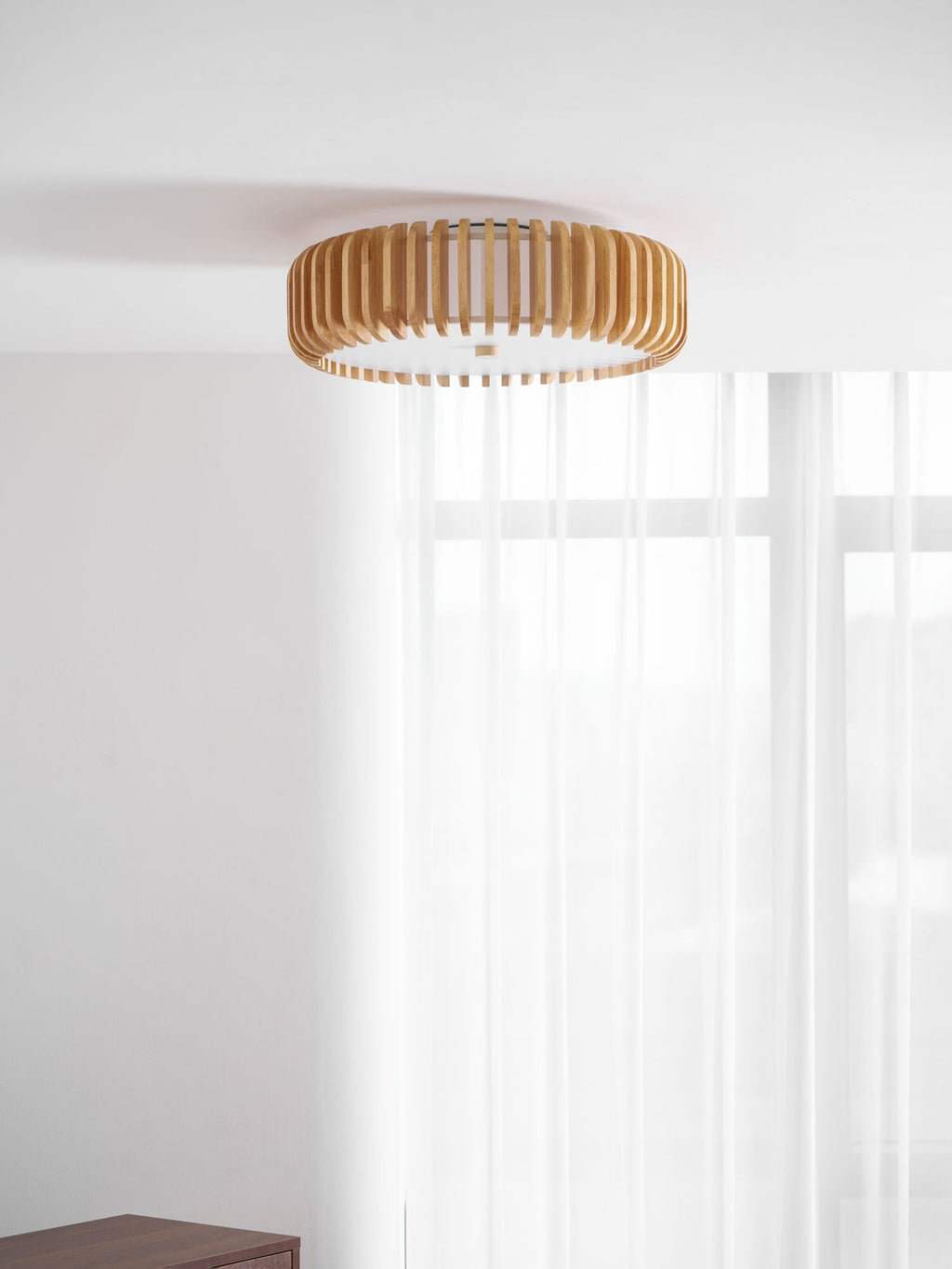 Mounted in a room corner with pale walls, this Clérachic ceiling light hangs near sheer curtains.