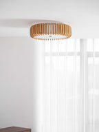 Mounted in a room corner with pale walls, this Clérachic ceiling light hangs near sheer curtains.