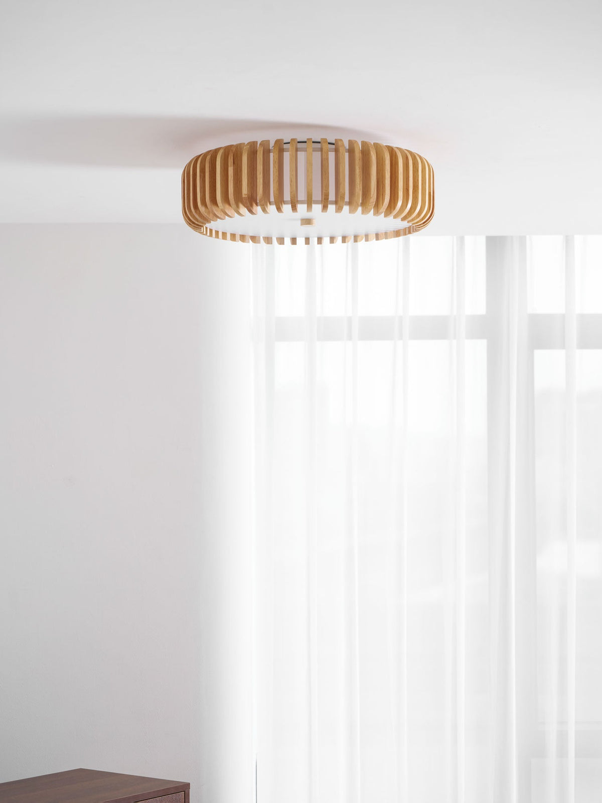 Mounted in a room corner with pale walls, this Clérachic ceiling light hangs near sheer curtains.