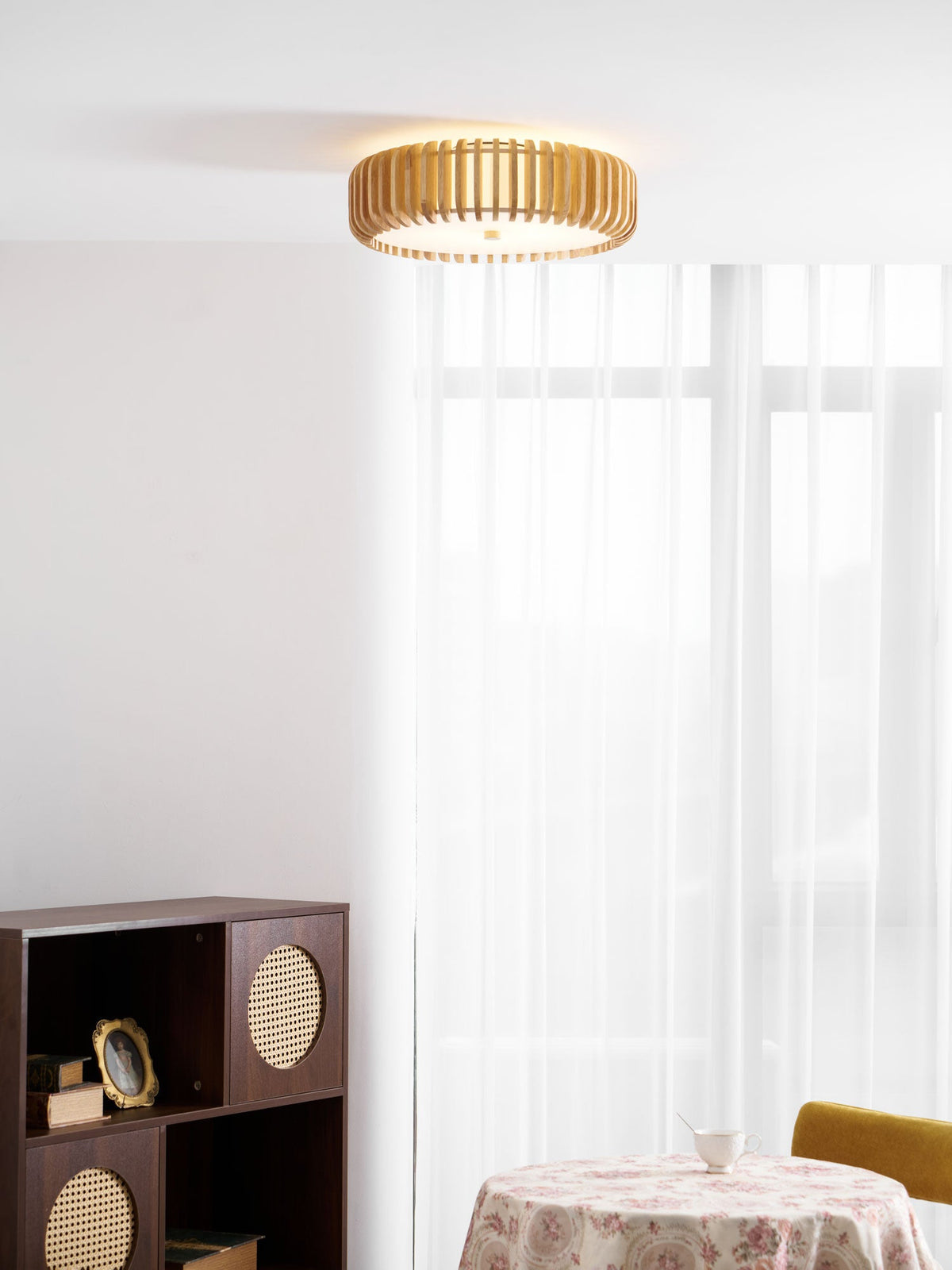 A dressed table and sheer curtains sit in the corner beneath this Clérachic ceiling light, lit.