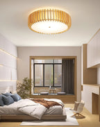 A window seat styled with cushions and potted plants sits below this Clérachic ceiling light, lit.