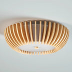 Close angled underside view of this Clérachic ceiling light lit, slats glowing against a pale blue backdrop.