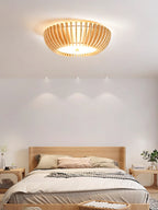Striped pillows dress the bed below this Clérachic ceiling light, lit, recessed downlights either side.