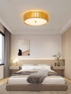 Framed artwork and matching nightstands flank the bed below this Clérachic ceiling light, lit.
