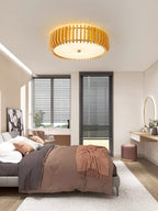 A round mirror on a dressing table sits below this Clérachic ceiling light, lit, near the bed.