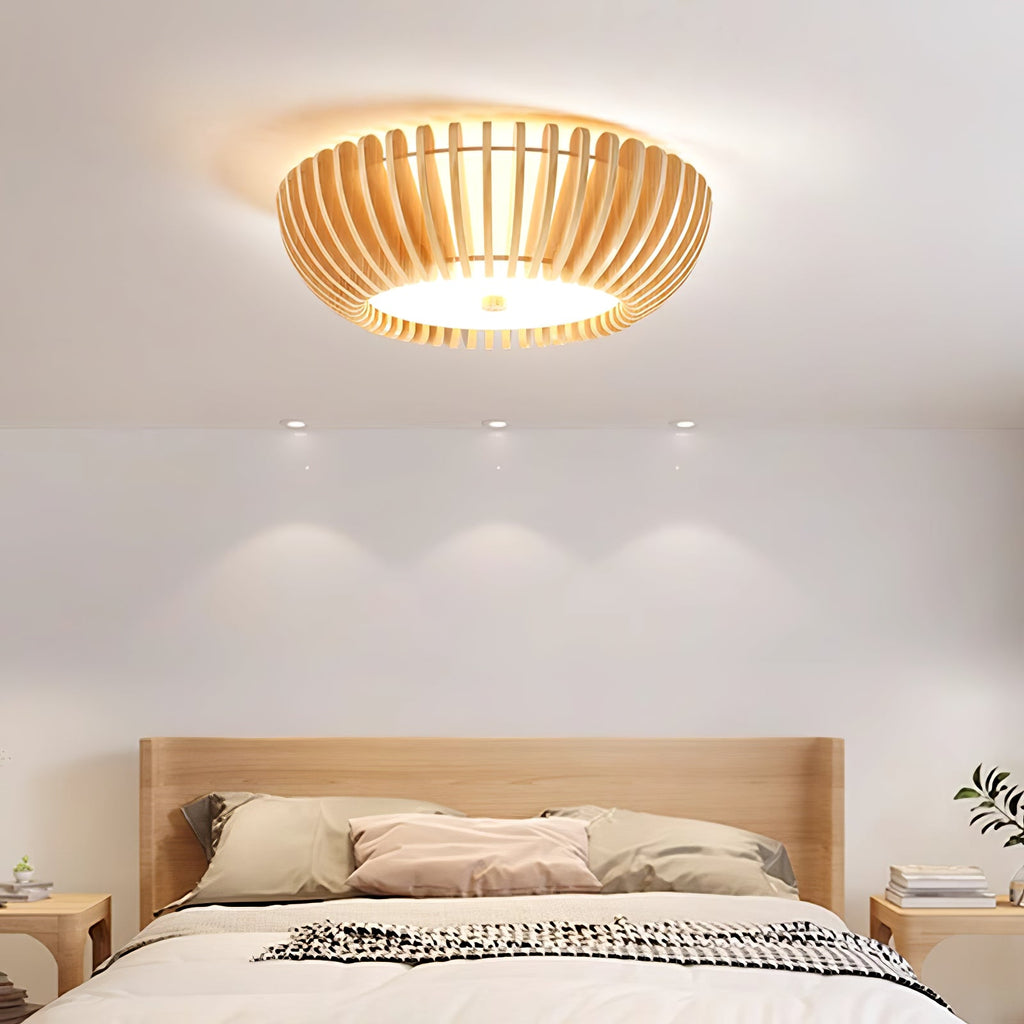 Recessed downlights sit beside this Clérachic ceiling light, lit, above a bed dressed in striped bedding.