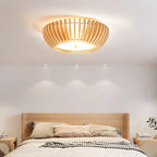 Recessed downlights sit beside this Clérachic ceiling light, lit, above a bed dressed in striped bedding.