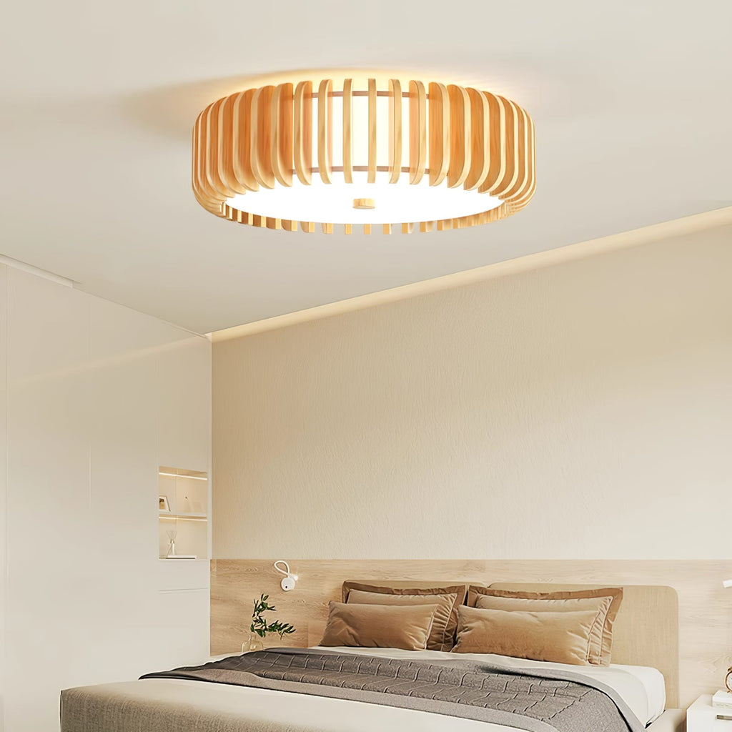 Patterned cushions dress the bed below this Clérachic ceiling light, lit, against a cream wall.