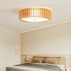 Patterned cushions dress the bed below this Clérachic ceiling light, lit, against a cream wall.
