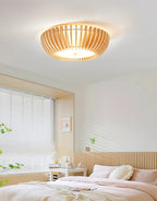 Dark-striped bedding and closed blinds sit below this Clérachic ceiling light, lit, in a bedroom.