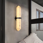 The black-band sconce lit beside a black-framed window, a pale sofa in the foreground.