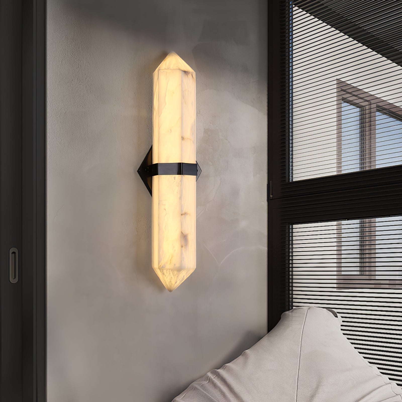 The black-band sconce lit beside a black-framed window, a pale sofa in the foreground.