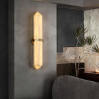 Wider view of the lit sconce in the living room, the textured stone wall and plant to the right.