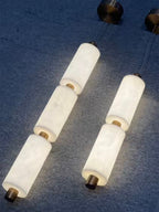 Angled real-room shot of two lit three-head Zovarion pendants against a deep blue textured wall.