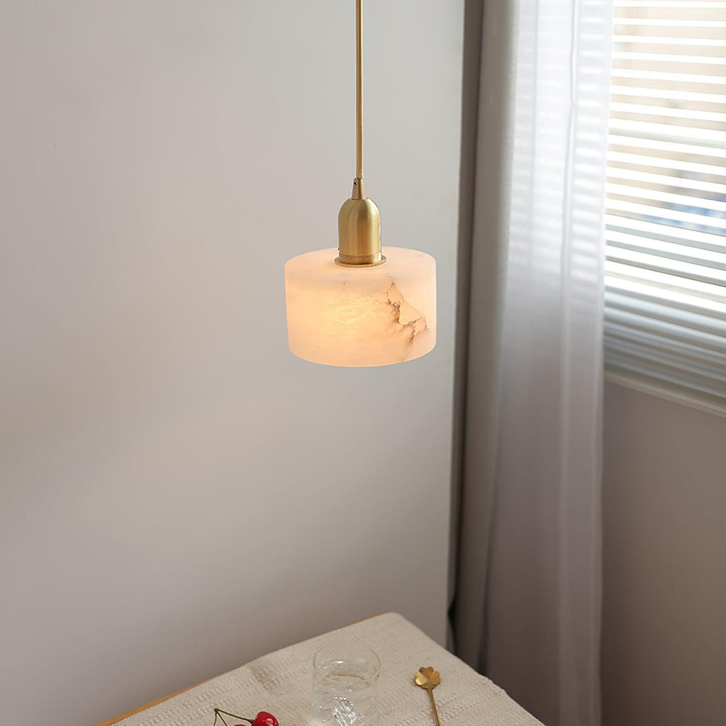 Brio pendant hanging beside a curtained window, lighting a small side table set with a glass and cherries.