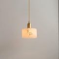 The Brio pendant's polished brass socket and slender brass cord above its softly lit alabaster drum shade.