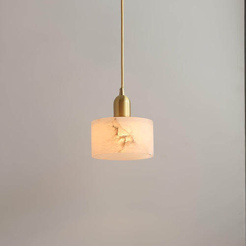 The Brio pendant's polished brass socket and slender brass cord above its softly lit alabaster drum shade.
