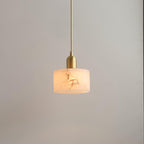 Brio alabaster pendant light lit against a soft grey wall, its slim brass stem holding a glowing veined drum shade.
