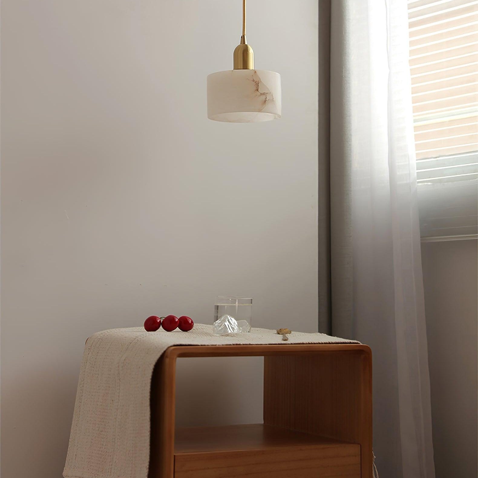 Brio pendant switched off above a wooden bedside cabinet, showing the alabaster shade's natural brown veining.