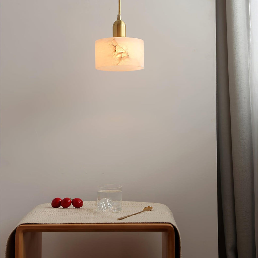 Brio pendant lit above a wooden side table, the alabaster shade casting a warm glow across the pale wall.