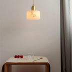 Brio pendant lit above a wooden side table, the alabaster shade casting a warm glow across the pale wall.