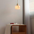 Angled view of the lit Brio pendant over a wooden bedside cabinet, with daylight coming from the window at right.