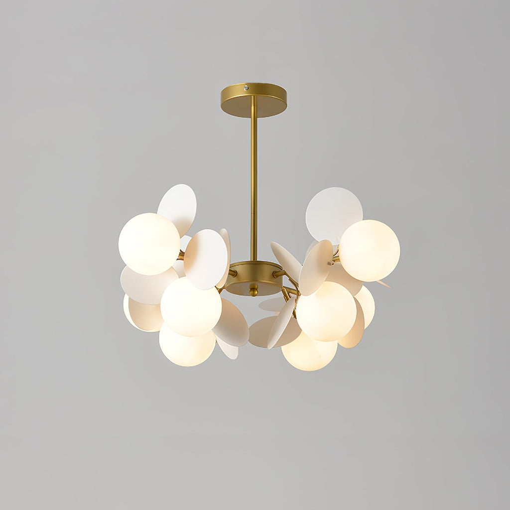 Tree chandelier with gold branching frame and top-open glass shades glowing in a styled living room