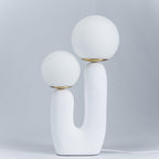 White glass globe table lamp lit on a side table