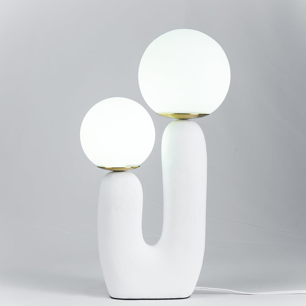 Sculptural table lamp glowing through a white glass globe