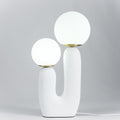 Sculptural table lamp glowing through a white glass globe