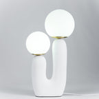 Sculptural table lamp glowing through a white glass globe