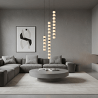 Three Orbique pendants at staggered drops over a round concrete coffee table in a grey living room
