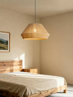 This Clérachic pendant lights a bedroom corner beside a wood bed frame and a small wood nightstand.