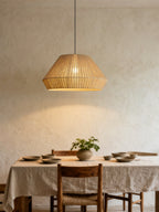 In beige linen, this Clérachic pendant hangs over a linen-draped table set with stoneware bowls against a plain rendered wall.